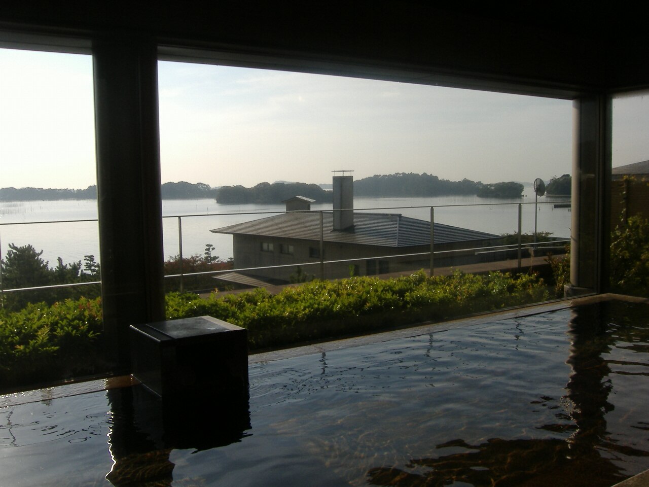 A serene indoor onsen bath with steam rising, perfect for a rainy day in Hakone.