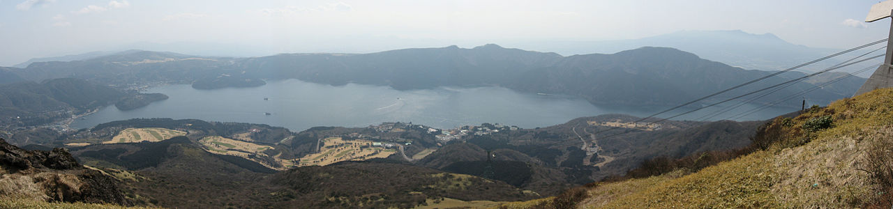 A wide panoramic view of Lake Ashi, showcasing its vastness and surrounding nature.