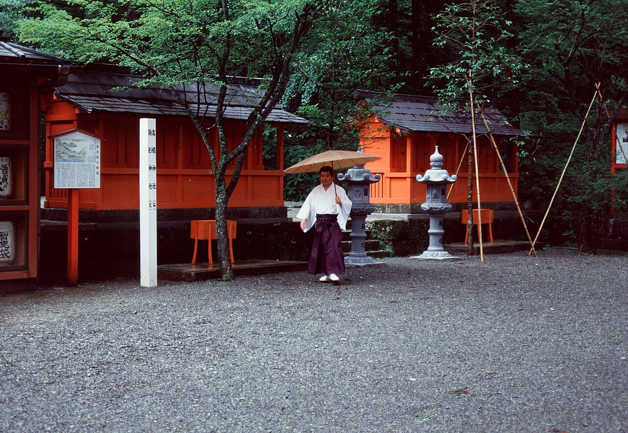 Stone steps and lanterns along the main approach path to Hakone Shrine, surrounded by tall trees.