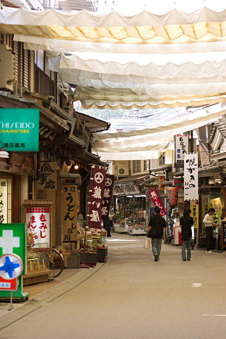 Bustling Omotesando shopping street on Miyajima Island, lined with souvenir shops and food stalls.