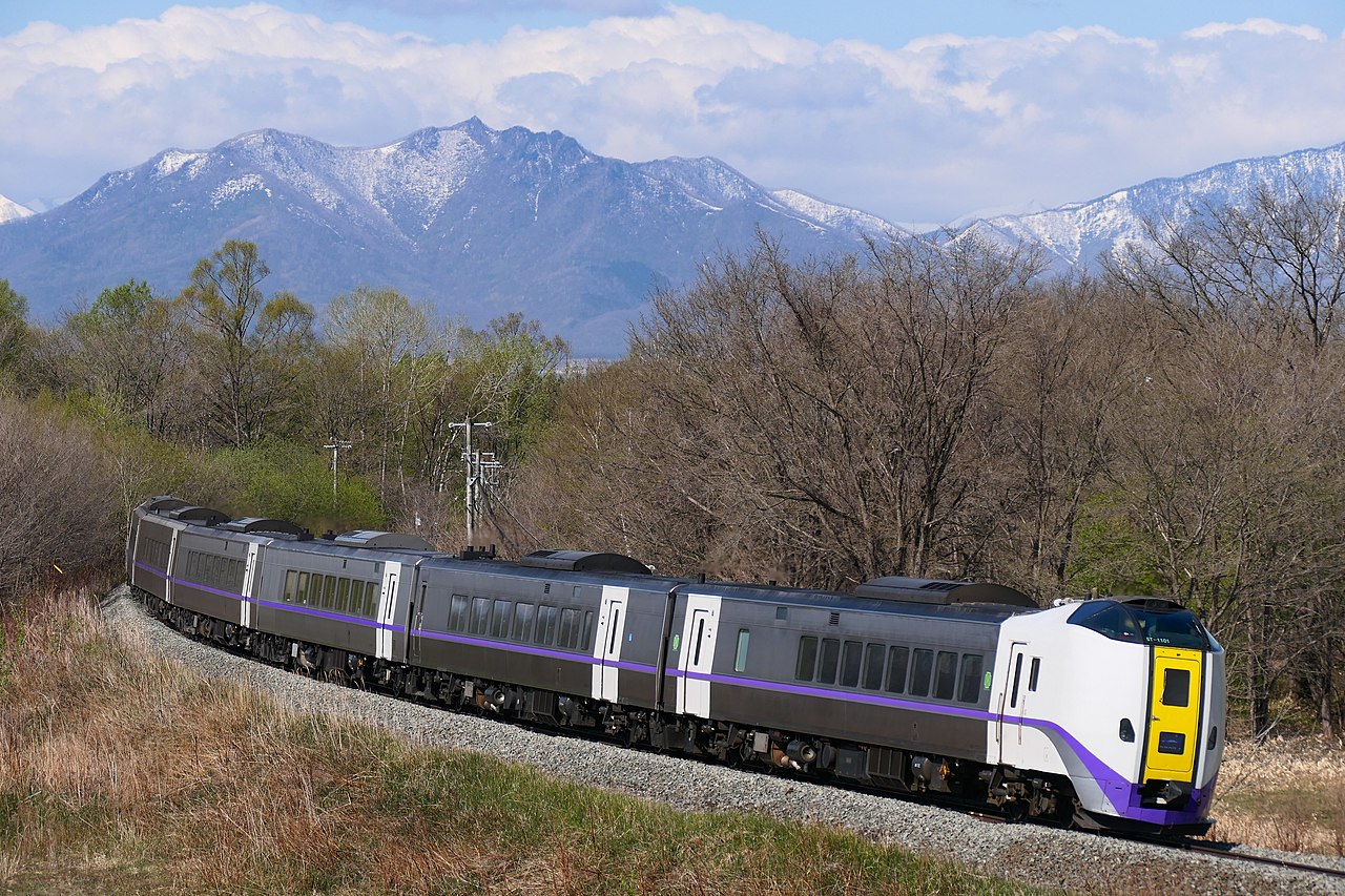 A JR Hokkaido train traveling through a scenic landscape, showcasing the region's natural beauty.