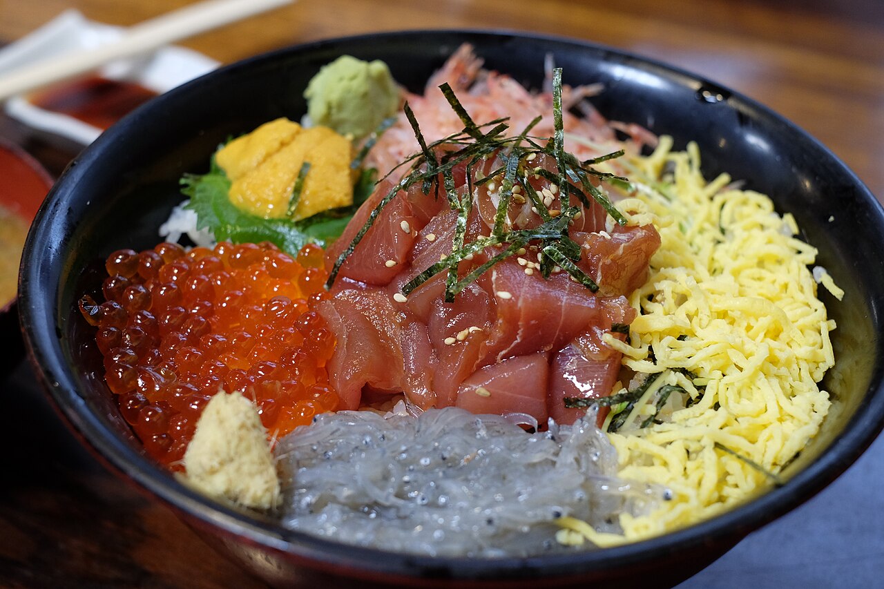 A vibrant Kaisendon (seafood rice bowl) featuring fresh uni, ikura, and various sashimi over rice.