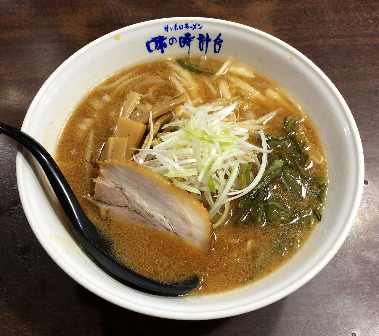 A steaming bowl of Sapporo miso ramen topped with corn, a pat of butter, chashu pork, and green onions.