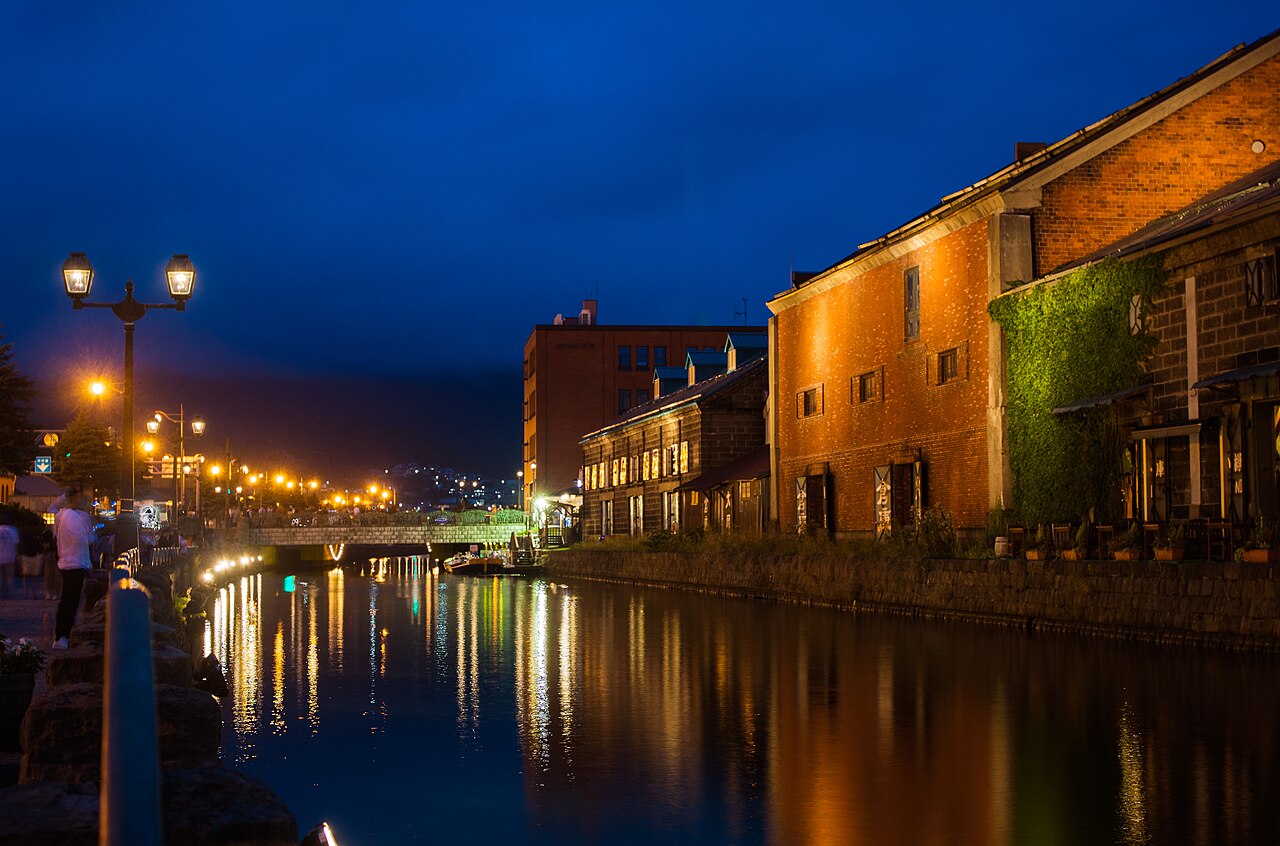 Otaru Canal at night with illuminated stone warehouses and gas lamps reflecting on the water