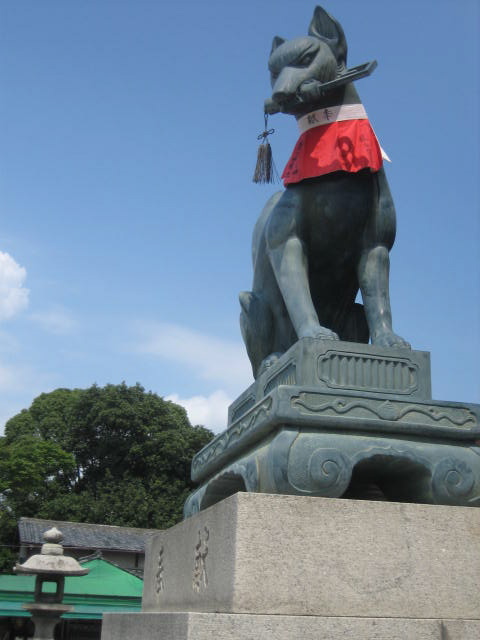 Stone fox statue with a key or jewel at Fushimi Inari Shrine