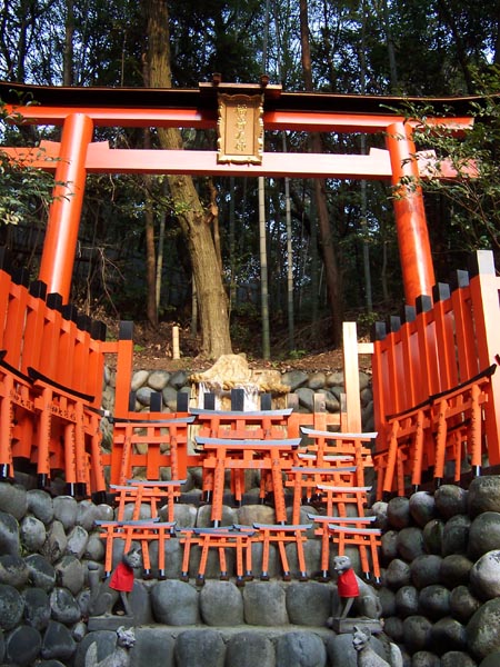 Small fox statues and torii gates at a sub-shrine along the Fushimi Inari trail