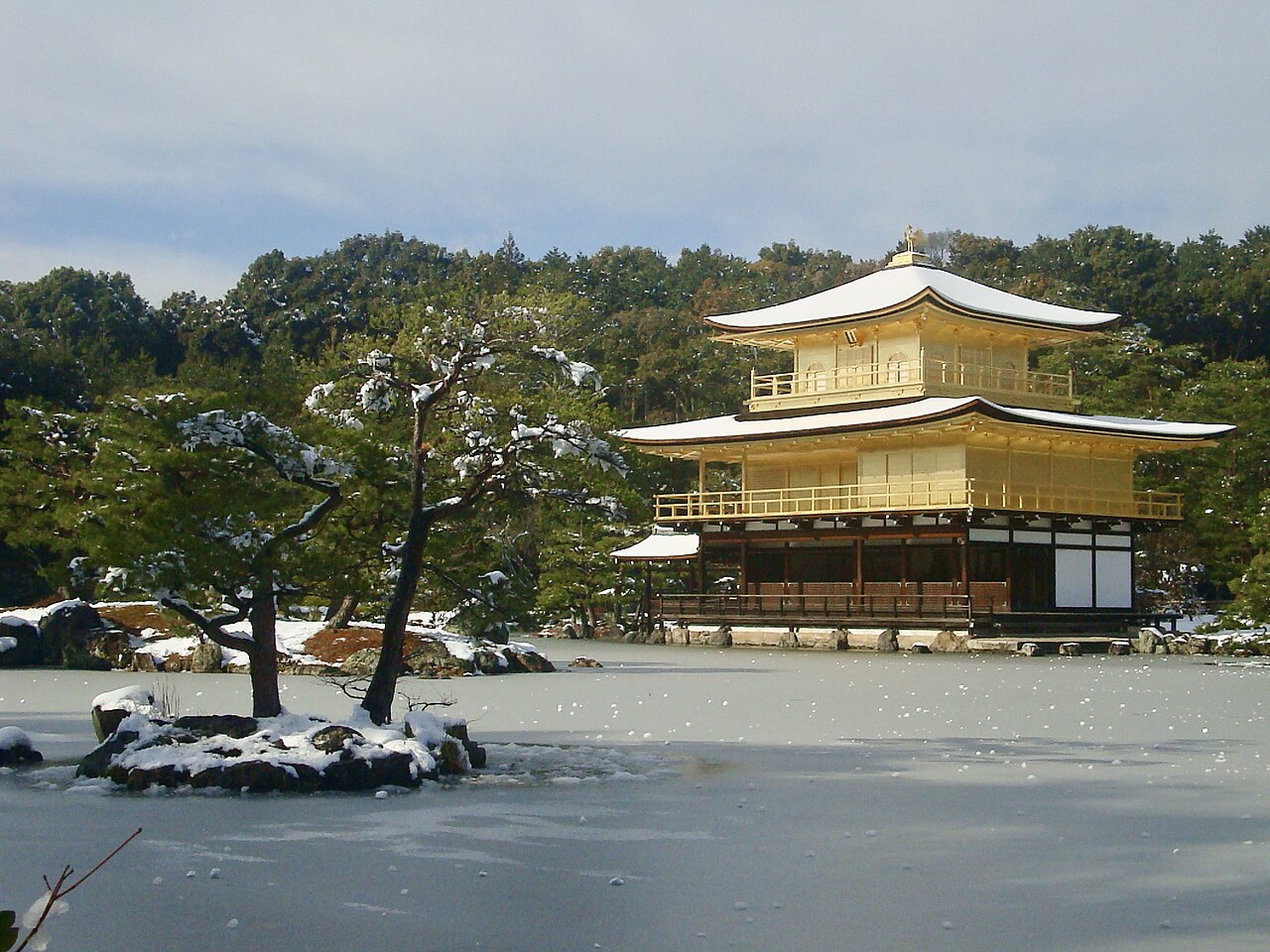 Kinkaku-ji Golden Pavilion covered in snow during winter, reflected in the still pond.