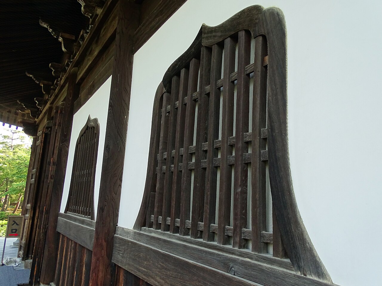A serene view of a raked gravel garden and moss from a covered wooden corridor at Kennin-ji Temple on a rainy day.