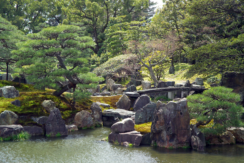 Scenic view of Nijo Castle's Ninomaru Garden featuring a large pond, carefully arranged stones, and manicured trees