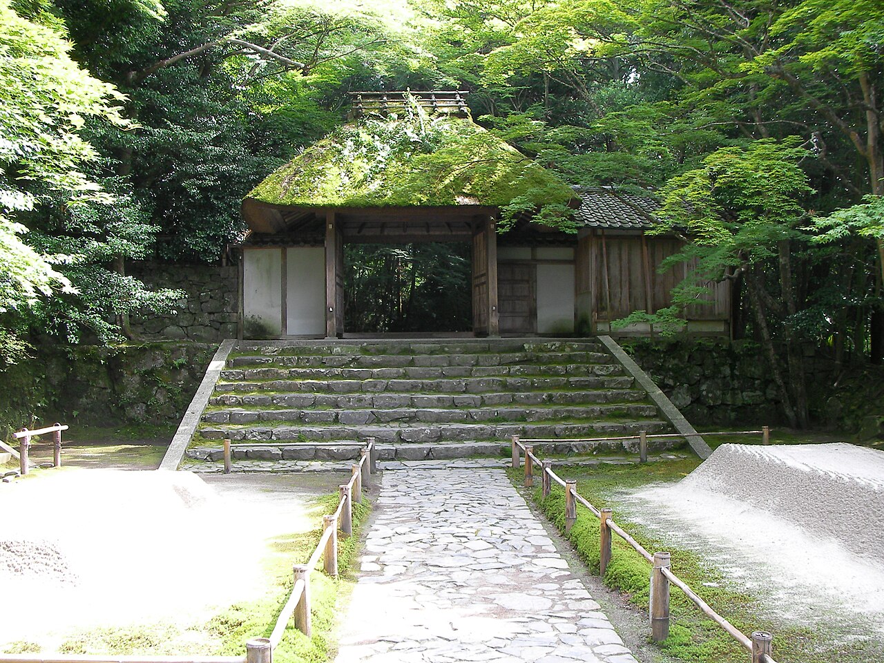 The moss-covered thatched gate of Honen-in Temple, nestled among trees, offering a serene entrance.