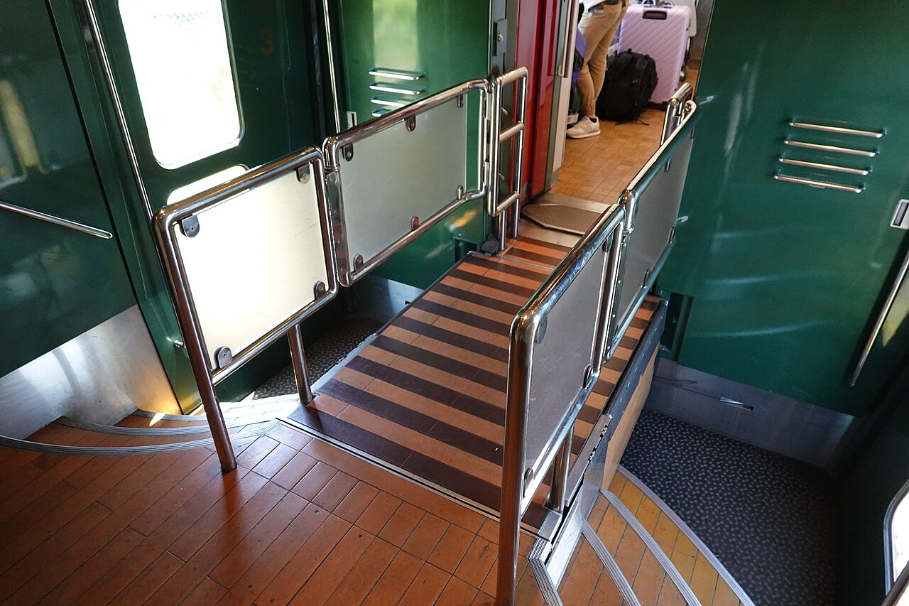 Interior of the Yufuin no Mori sightseeing train, featuring elegant wood paneling and large windows.