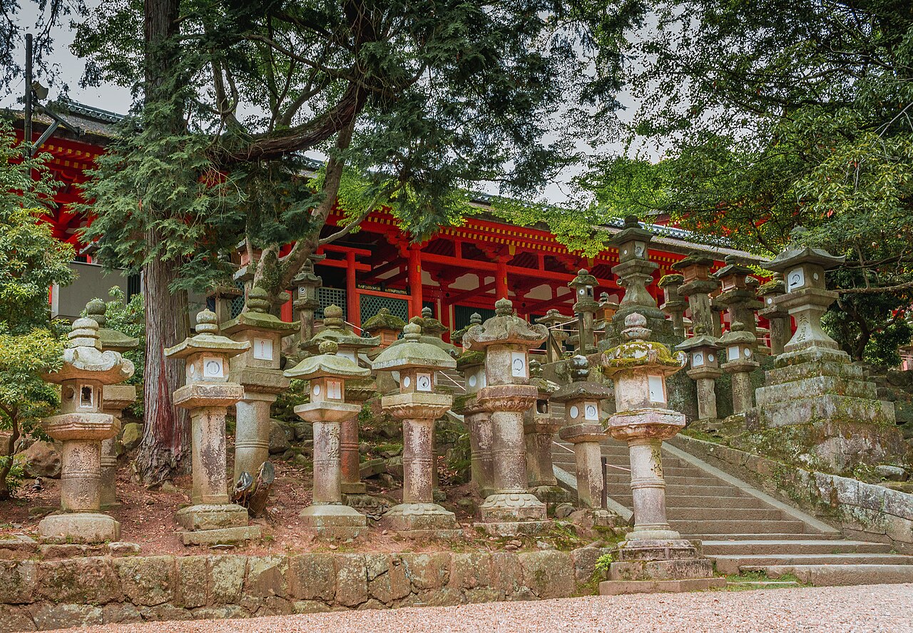 A path lined with moss-covered stone lanterns leading to Kasuga Taisha Shrine