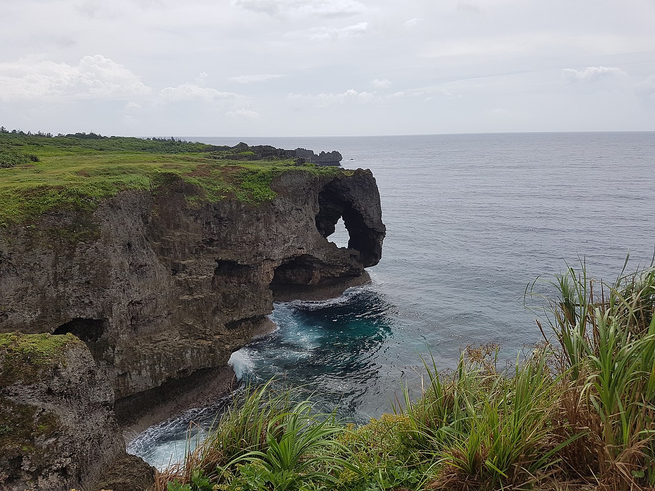 Scenic view of Cape Manzamo's elephant trunk rock formation with clear blue water