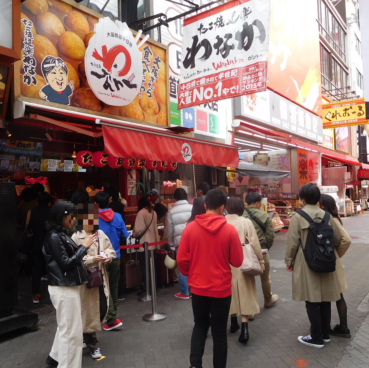 Vendor preparing takoyaki octopus balls on a hot griddle in Dotonbori