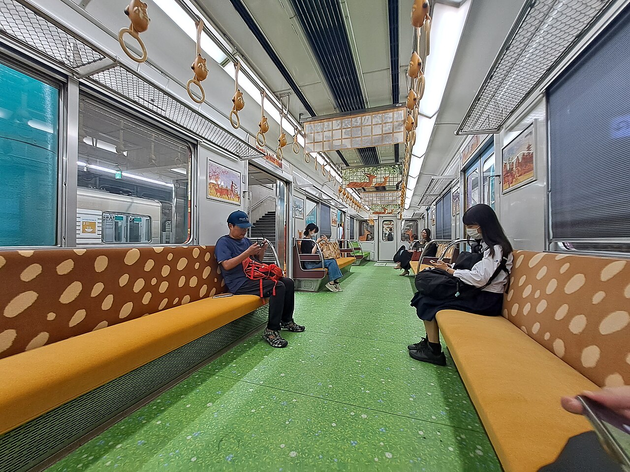 Red and orange Kintetsu Railway train at a station platform