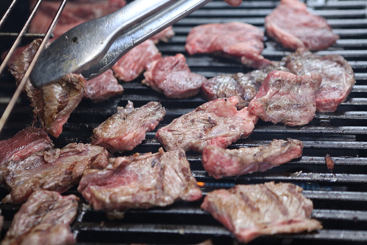 Slices of premium A5 grade Wagyu beef being grilled on a hot plate, a popular local specialty at Kuromon Market.