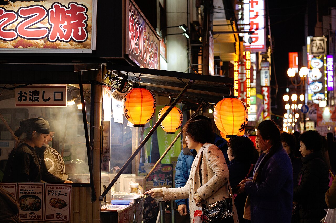 Freshly made takoyaki octopus balls being cooked on a griddle at a street stall in Osaka