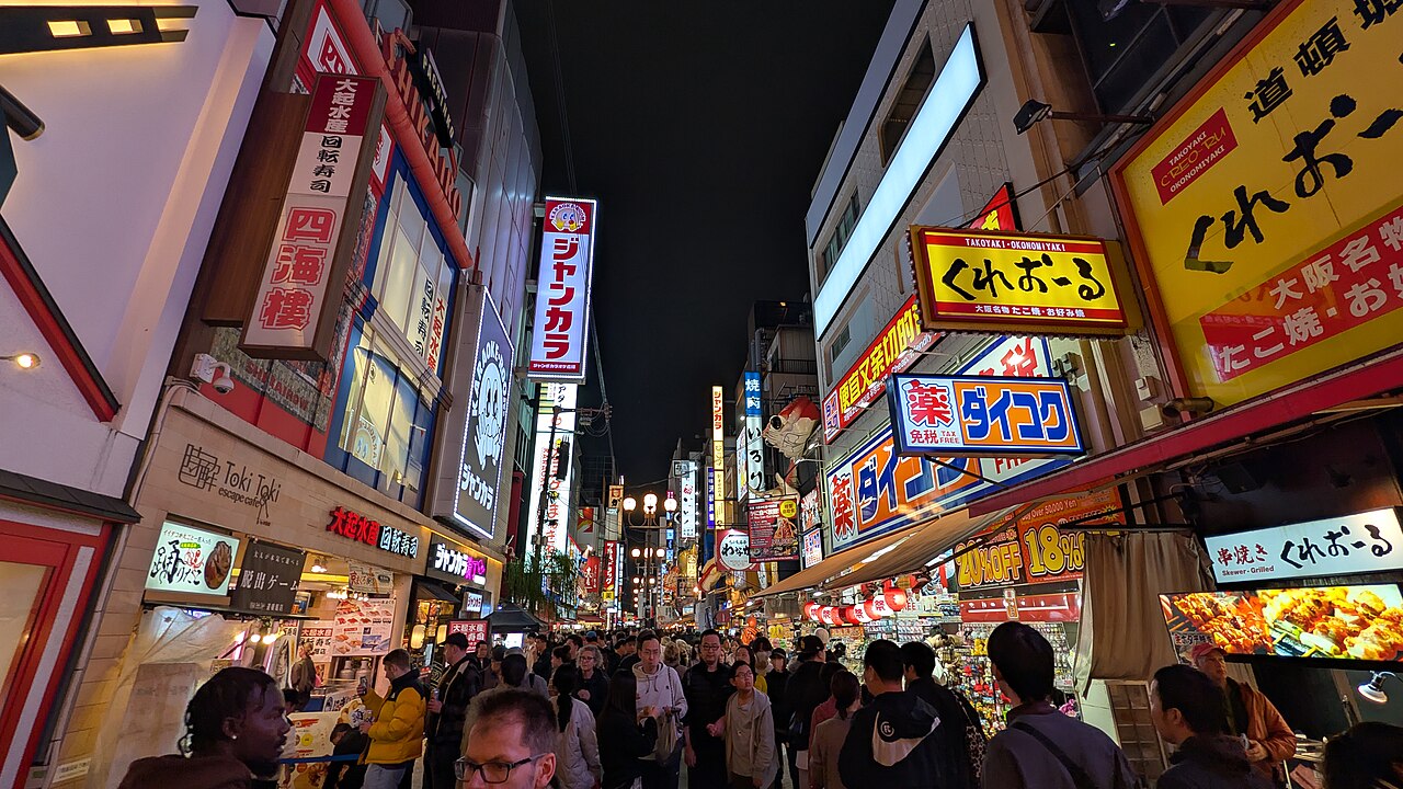 Vibrant Dotonbori street at night with various food stalls and neon signs