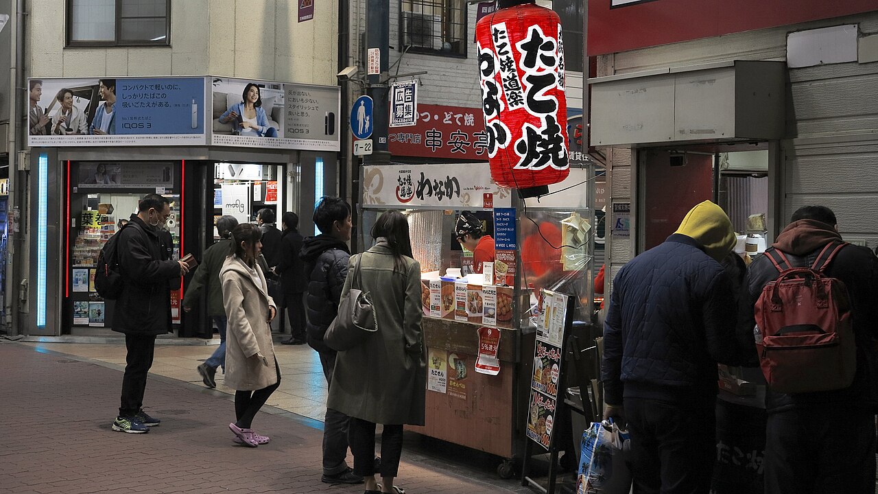 Children watching takoyaki being made at a street stall in Osaka