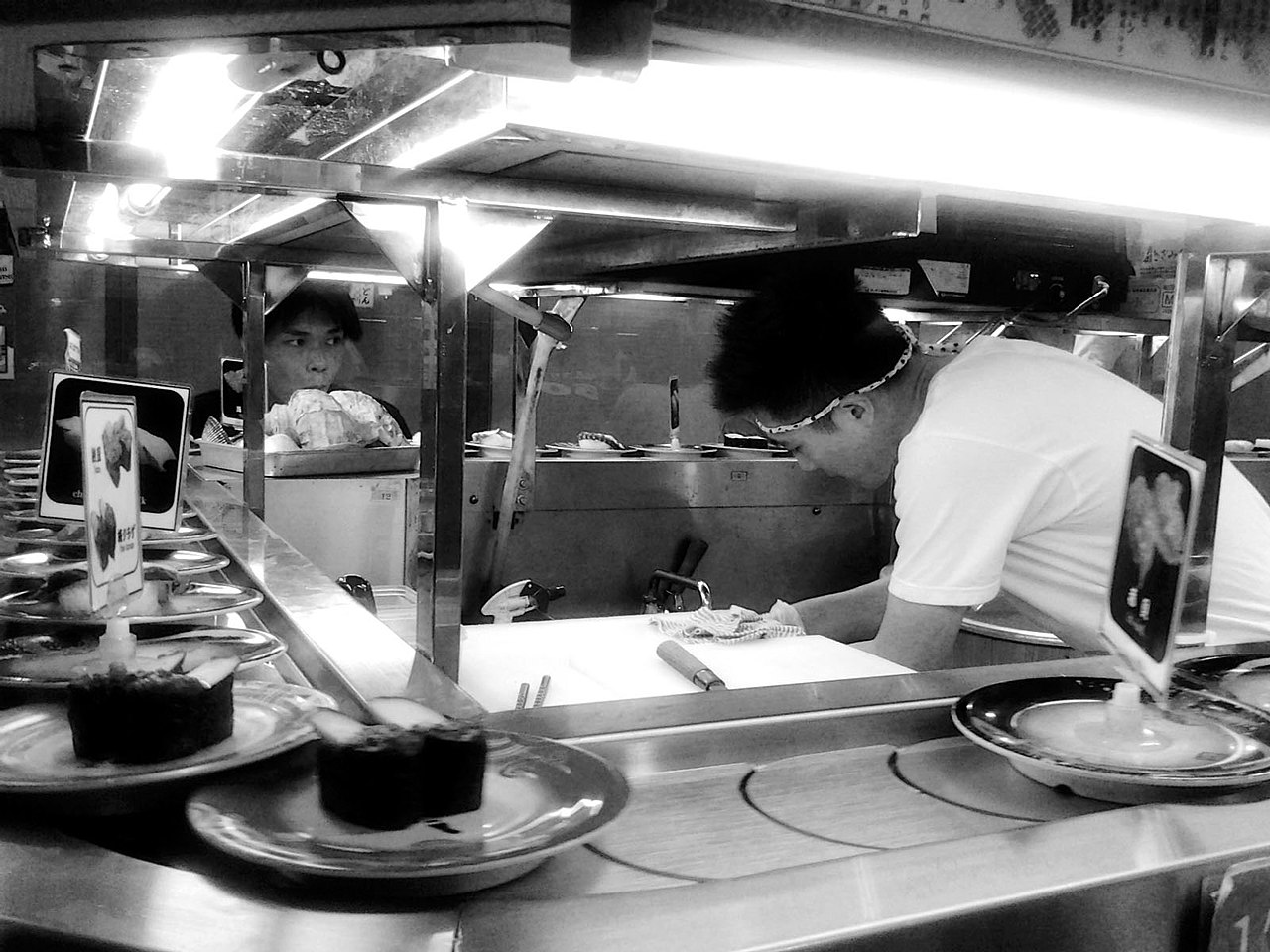Children picking sushi plates from a conveyor belt at a sushi restaurant in Osaka