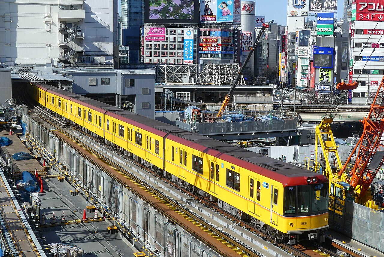 An orange Tokyo Metro Ginza Line train at a subway station.