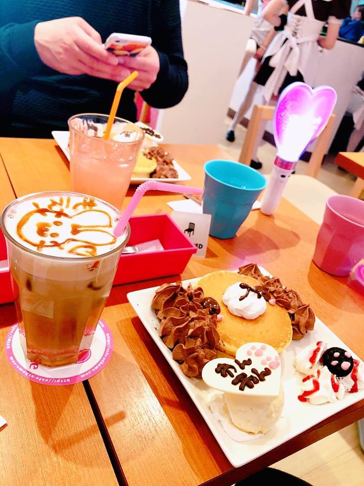Interior of a themed maid cafe in Akihabara, with staff dressed in maid costumes interacting with customers