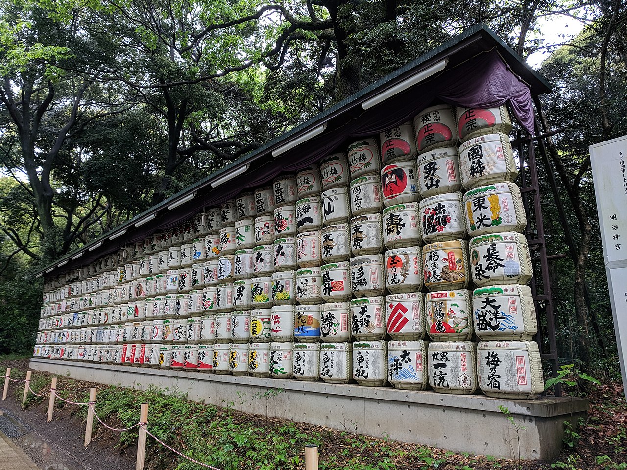 Decorative sake barrels displayed along the path leading to the main shrine buildings at Meiji Shrine.