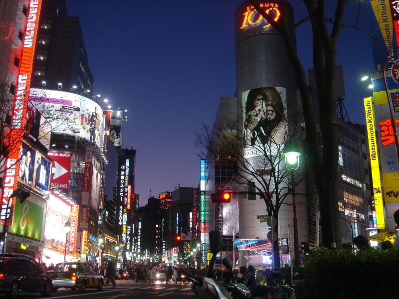 Vibrant street scene in Shibuya at night, with illuminated restaurants and bars
