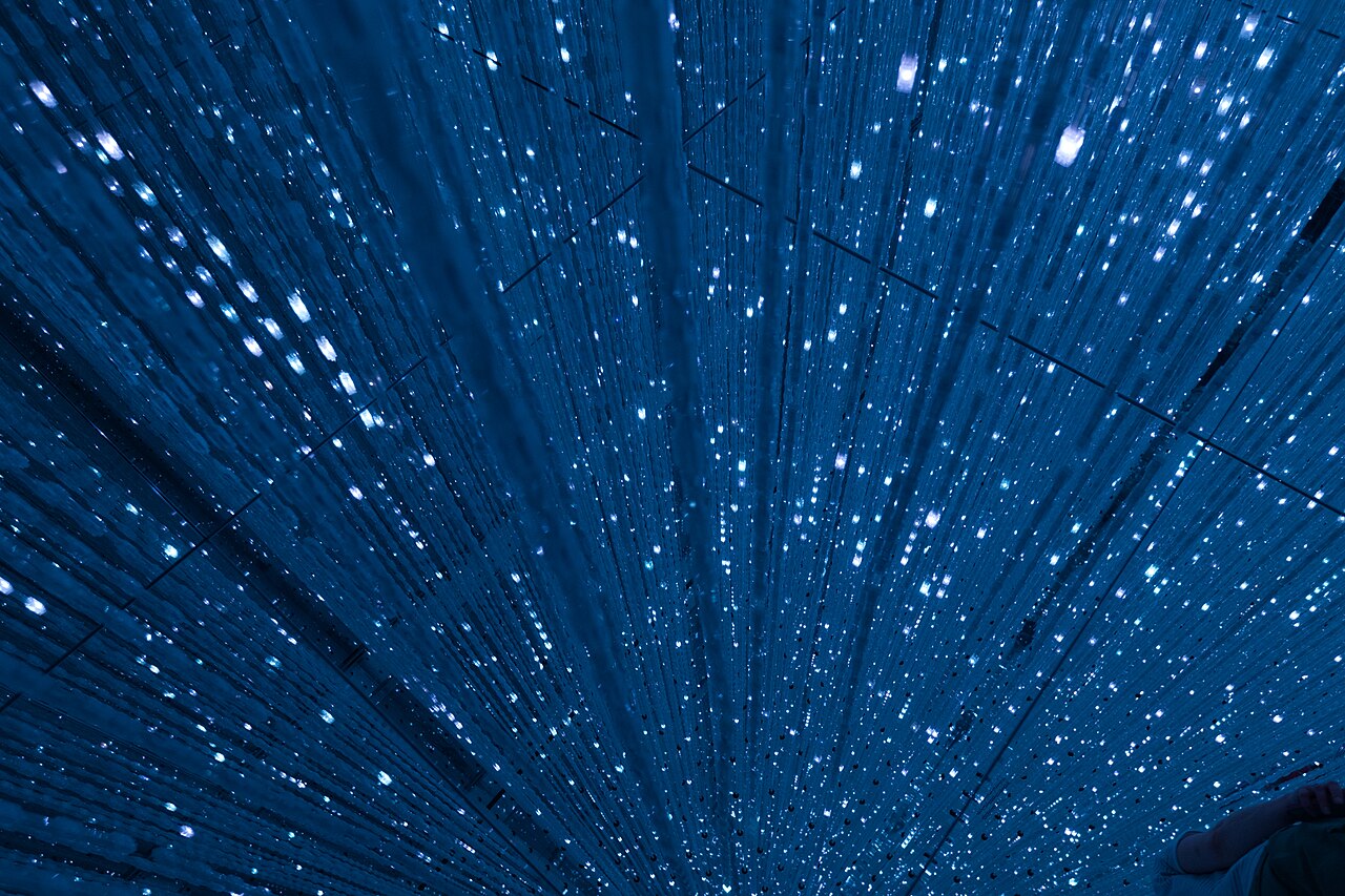 Visitors interacting with digital art installations at teamLab Planets Tokyo, surrounded by vibrant light and water features