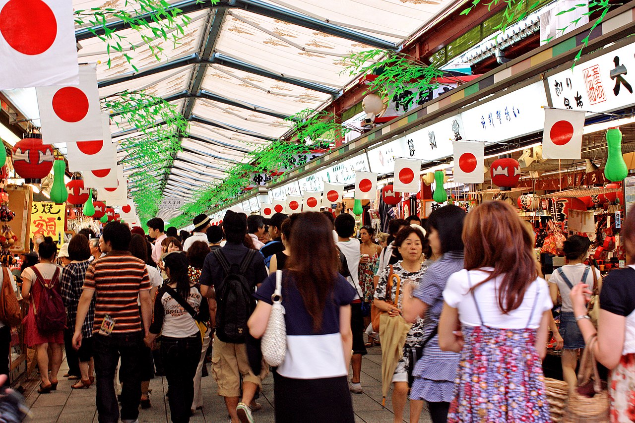 People walking under the covered arcade of Nakamise-dori in Asakusa, with traditional shops lining the path towards Senso-ji Temple