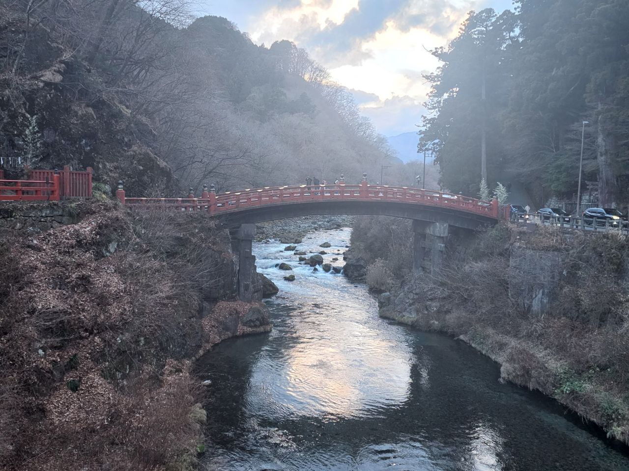 Red lacquered Shinkyo Bridge spanning a river in Nikko, surrounded by trees