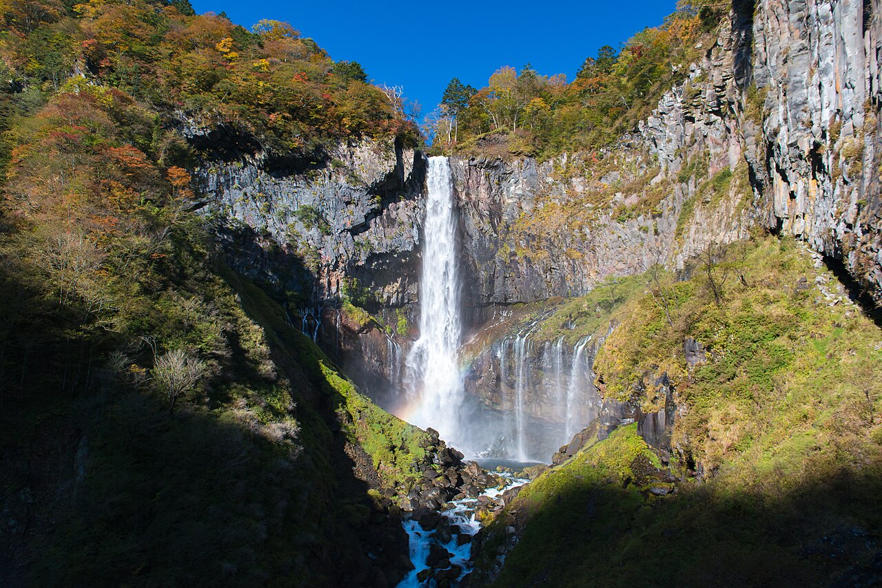 Majestic Kegon Falls cascading into a pool, surrounded by lush greenery in Nikko