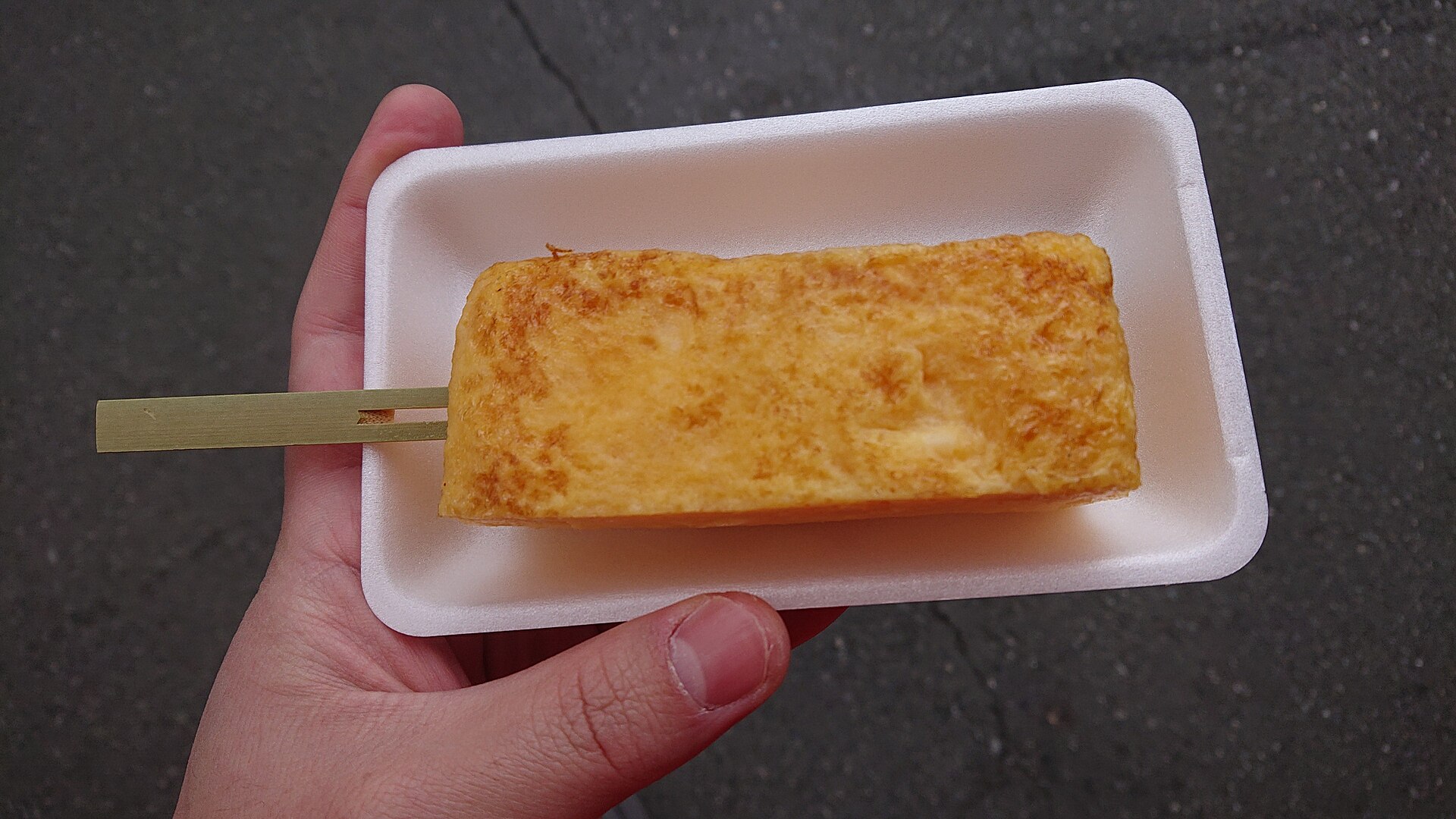 Grilled sweet tamagoyaki served on a stick from a stall at Tsukiji Outer Market.